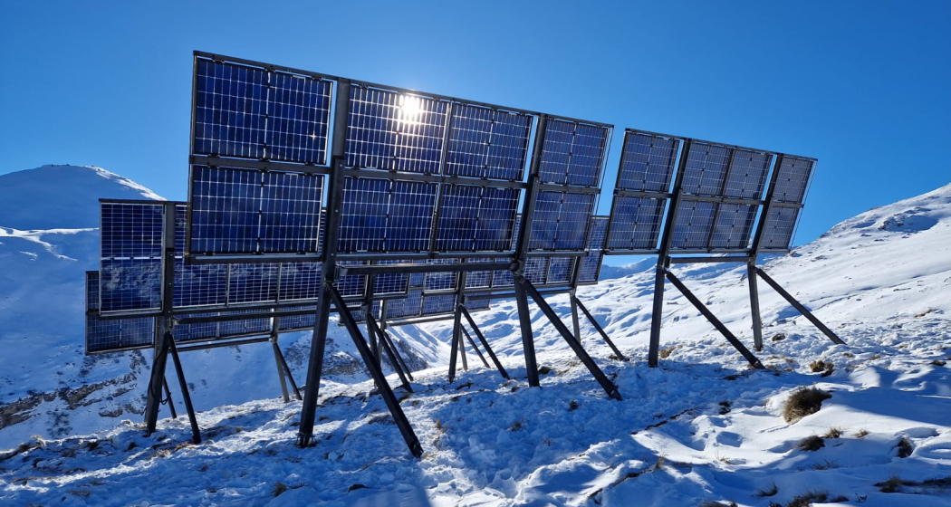 ALPIN QUATTRO DigitalTwin Solaranlage in alpiner Schneelandschaft mit blauen Photovoltaikmodulen vor klarem Himmel.