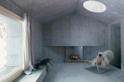 minimalistischer Raum aus Beton (Foto: © Gaudenz Danuser) Minimalistischer Raum aus Beton mit Kamin, Sessel und Fell, Lichtöffnung in der Decke