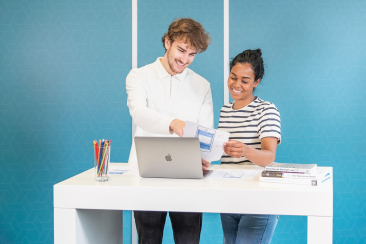 Zwei Menschen schauen auf einen Laptop