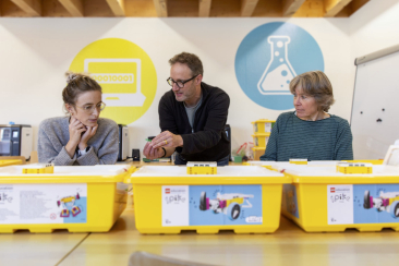 Ein Mann und eine Frau bedienen gemeinsam einen 3D-Drucker in einem modernen Bildungsumfeld. Das Bild vermittelt praxisnahes Lernen im digitalen Wandel.