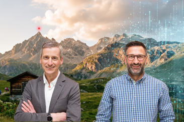 Zwei Männer vor einer Bündner Berglandschaft, die rechts in ein digitales Raster aus leuchtenden Bildpunkten übergeht. Links ein Holzstall und wandernde Personen. Namensschilder weisen die beiden als Jon Erni (GRdigital) und Jan Koch (Bündner Gewerbeverband) aus. Darüber der Titel «Digitalisierung in Graubünden: Einiges erreicht und noch viel zu tun».